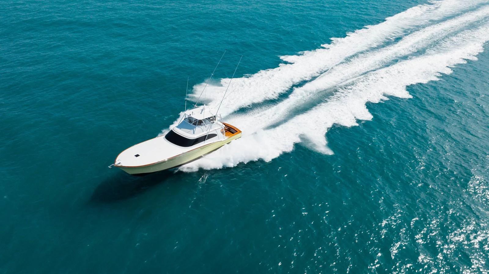A sleek yacht cruises swiftly across the open sea, leaving a trail of white wake behind. aboard QUEEN BEE Yacht for Sale