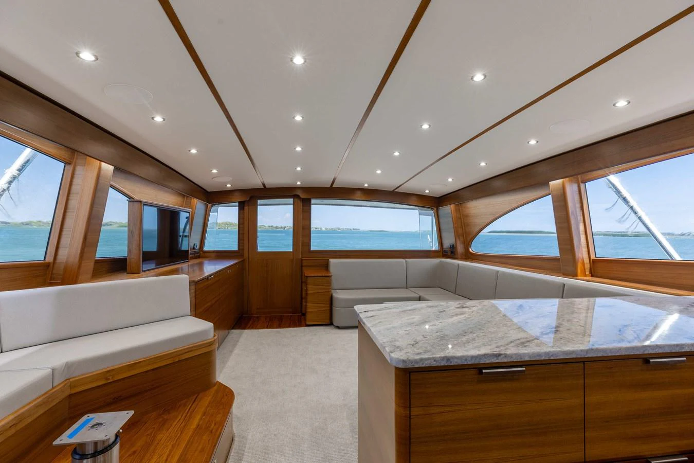 The salon features expansive windows, plush seating, and a modern design with a blend of wood and neutral tones. aboard QUEEN BEE Yacht for Sale