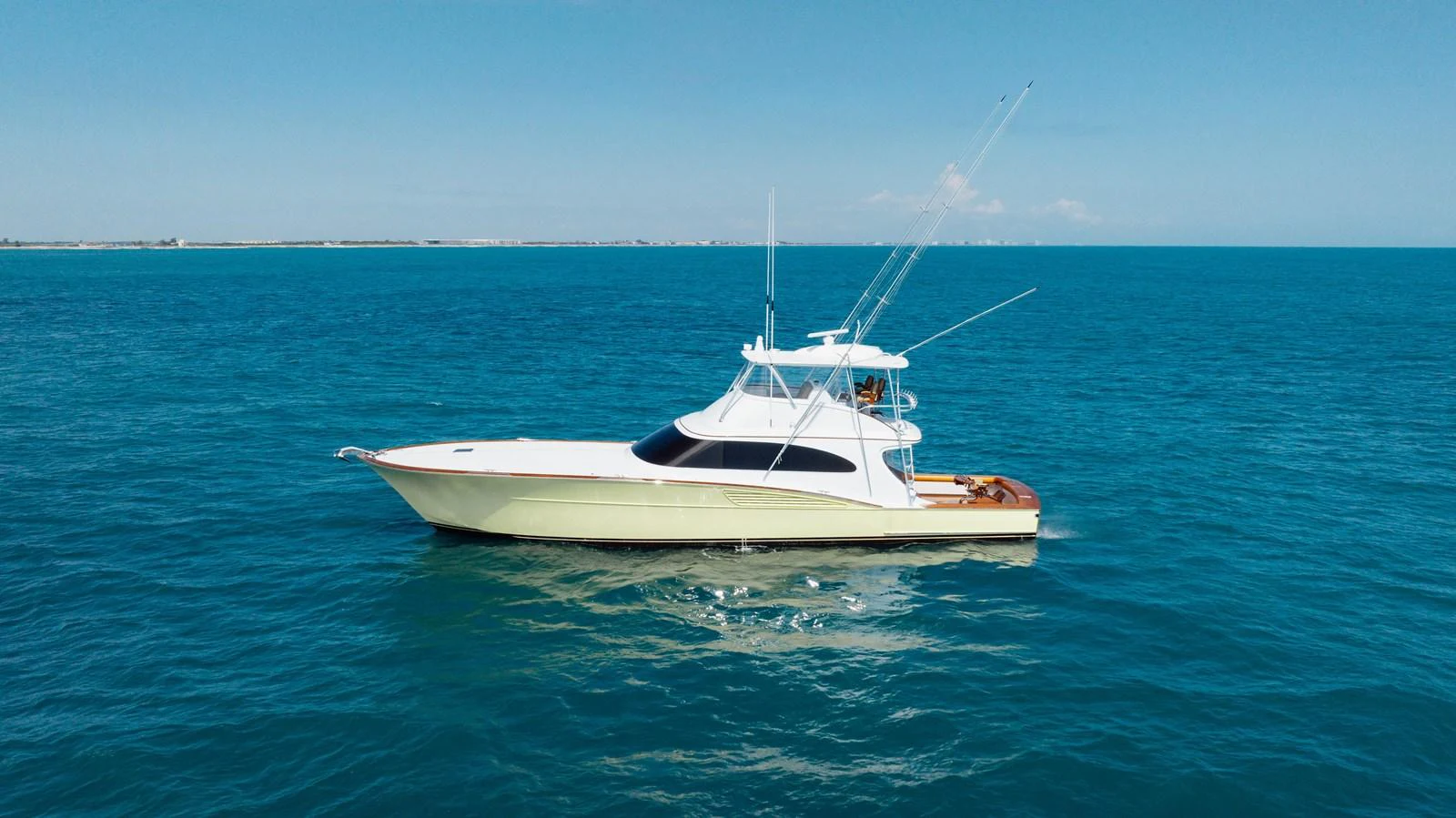 A sleek yacht cruises on calm, clear blue waters under a bright sky. aboard QUEEN BEE Yacht for Sale