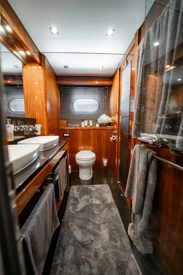 The yacht's bathroom features elegant wood paneling, dual sinks, and modern fixtures. aboard BLUE Yacht for Sale