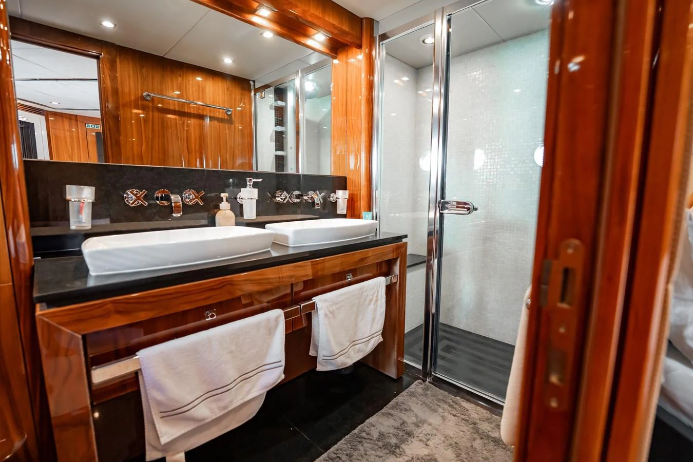 The yacht's bathroom features a luxurious double sink vanity and a spacious glass-enclosed shower. aboard BLUE Yacht for Sale