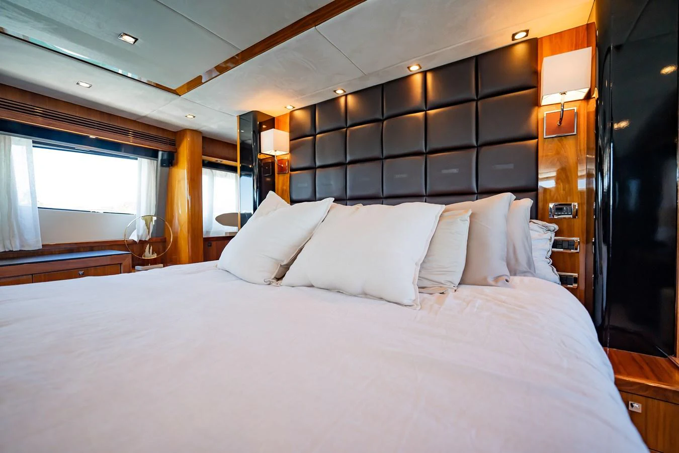 The master stateroom features a luxurious bed with plush pillows and elegant wood accents. aboard BLUE Yacht for Sale