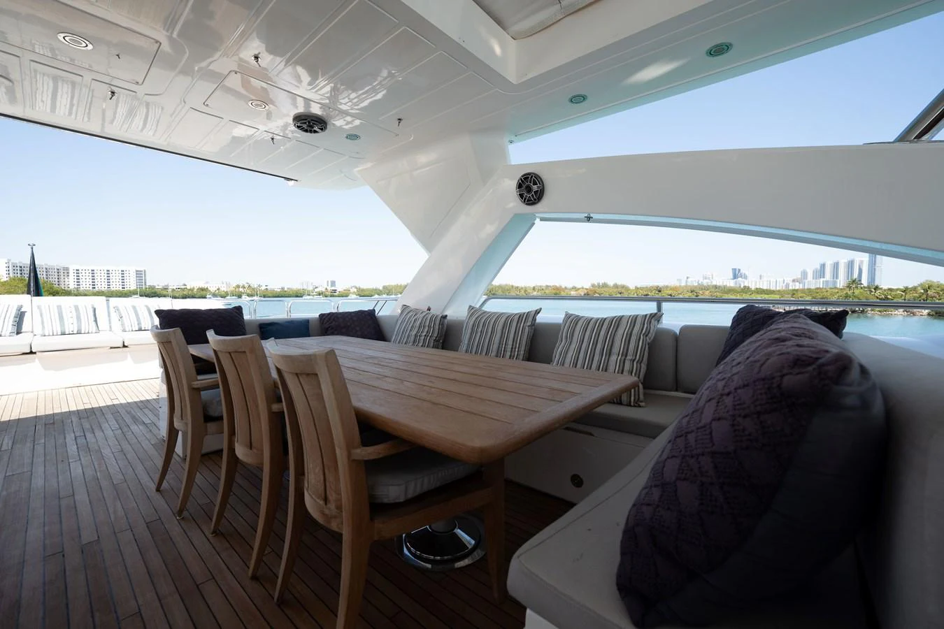 The aft deck features a spacious dining area with a wooden table and comfortable seating, offering stunning views of the water. aboard BLUE Yacht for Sale