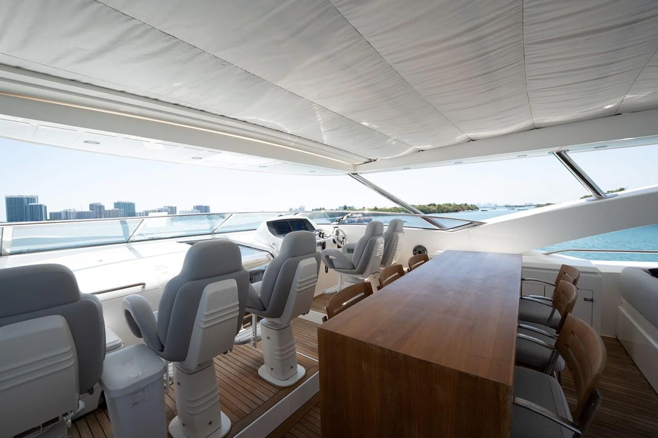 The helm area features multiple captain's chairs and a sleek wooden table, offering a panoramic view of the water. aboard BLUE Yacht for Sale