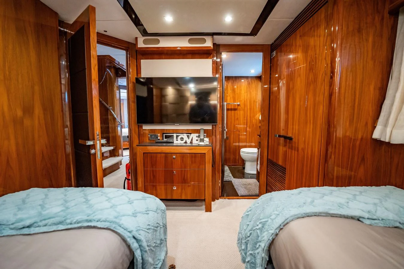The guest stateroom features twin beds, a flat-screen TV, and an ensuite bathroom with luxurious wooden finishes. aboard BLUE Yacht for Sale