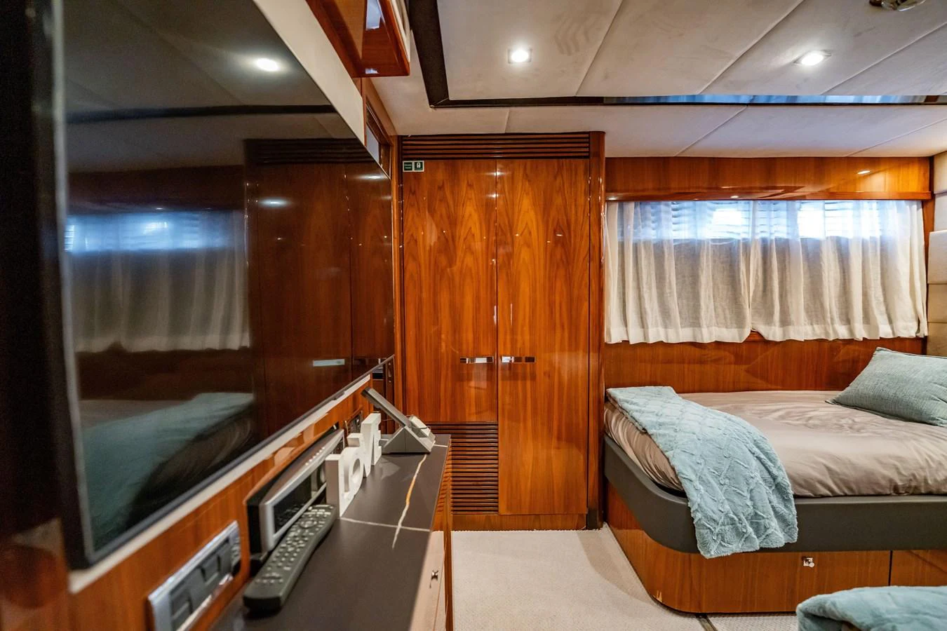 A cozy stateroom featuring a comfortable bed, wood paneling, and modern amenities. aboard BLUE Yacht for Sale