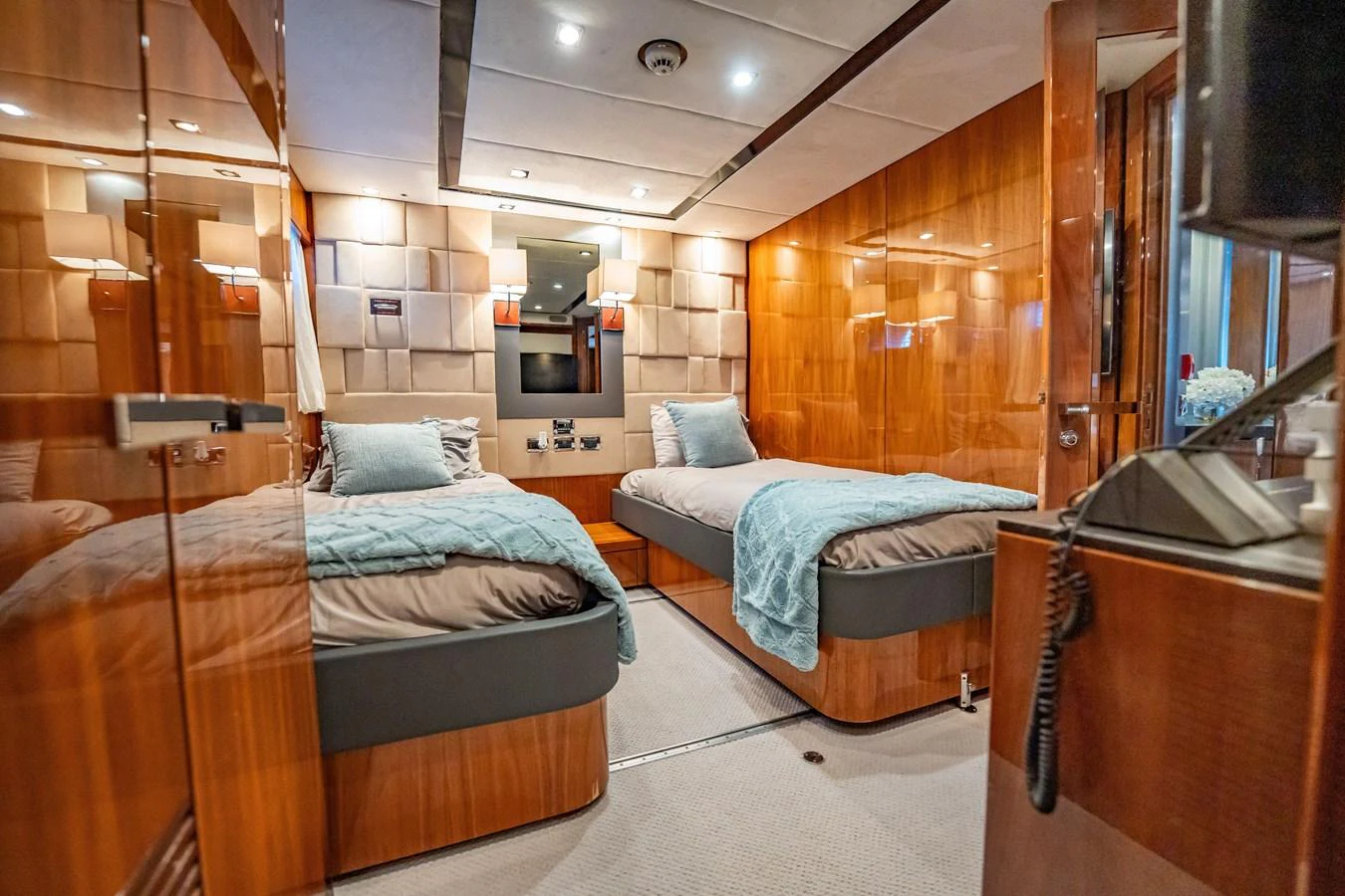 The twin stateroom features two single beds with luxurious bedding and warm wood paneling. aboard BLUE Yacht for Sale