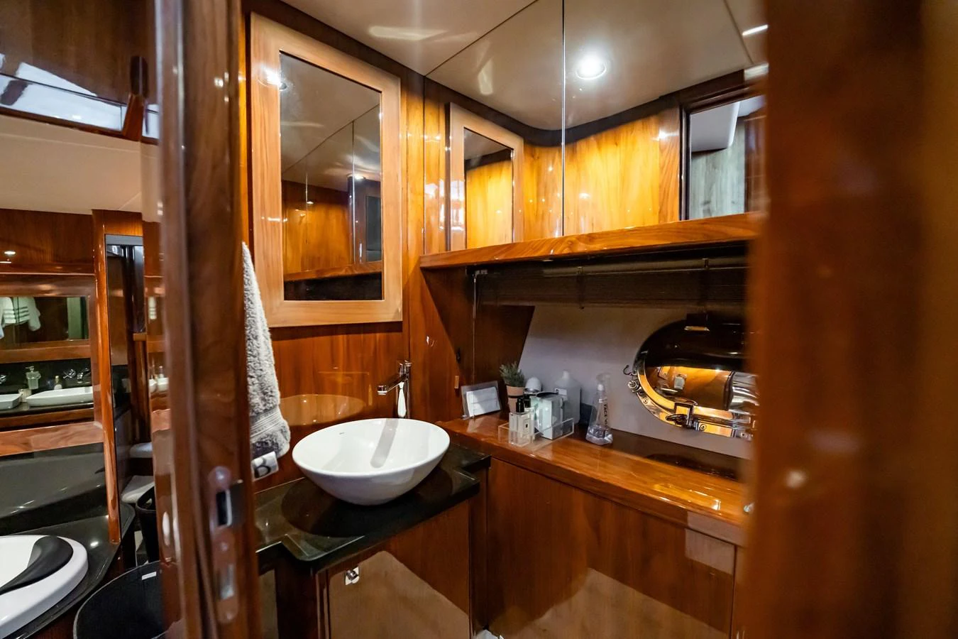 The yacht's bathroom features elegant wooden cabinetry and a modern vessel sink. aboard BLUE Yacht for Sale