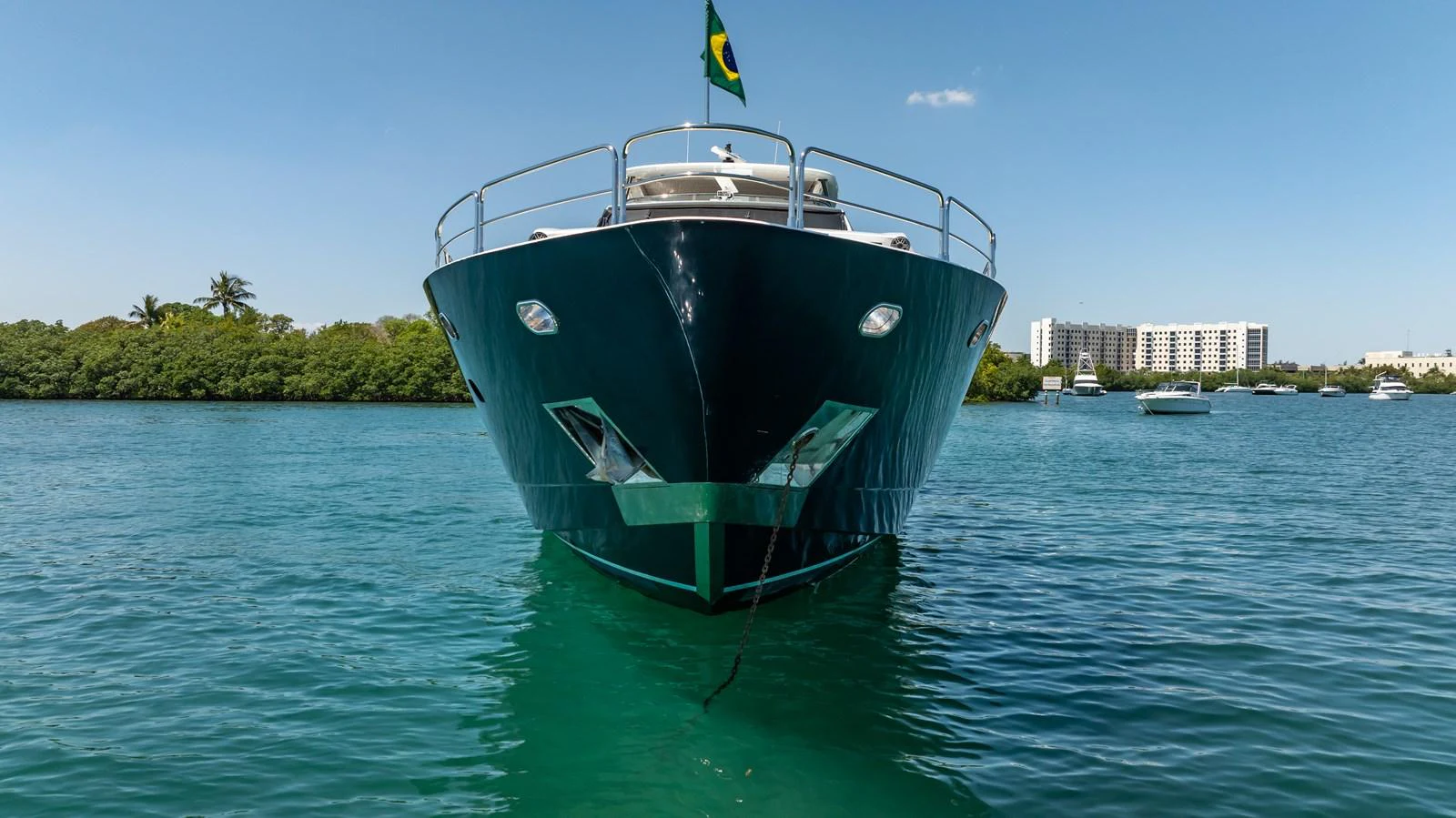A sleek yacht is anchored in calm waters, showcasing its impressive bow and modern design. aboard BLUE Yacht for Sale