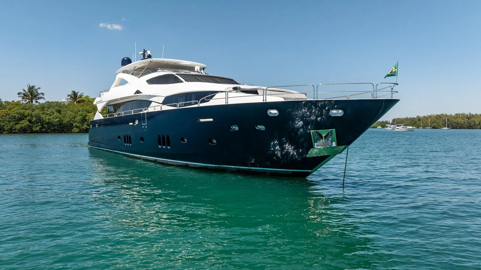 A sleek and modern yacht cruises gracefully on calm, turquoise waters under a clear blue sky. aboard BLUE Yacht for Sale