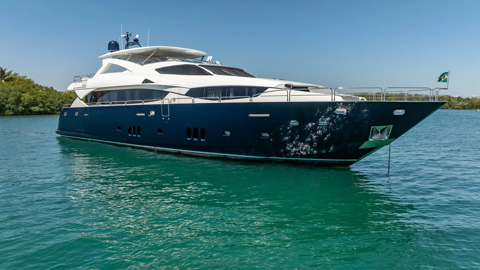 A sleek and modern yacht glides gracefully on calm turquoise waters under a clear blue sky. aboard BLUE Yacht for Sale