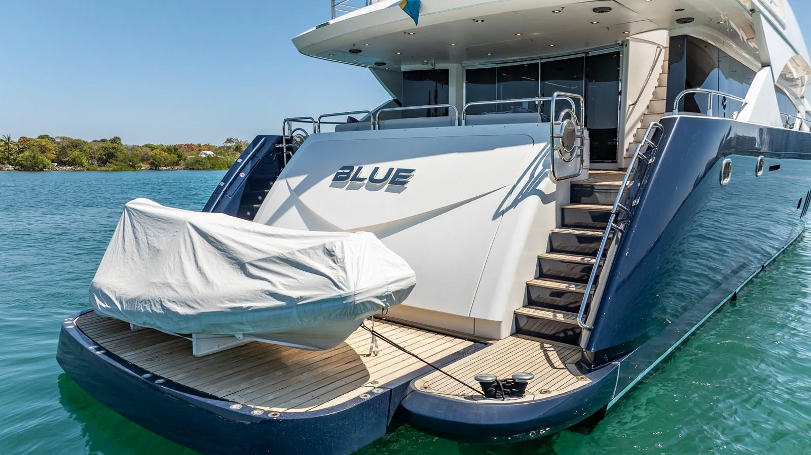 The yacht's aft deck features a covered tender and elegant stairway leading to the upper deck. aboard BLUE Yacht for Sale