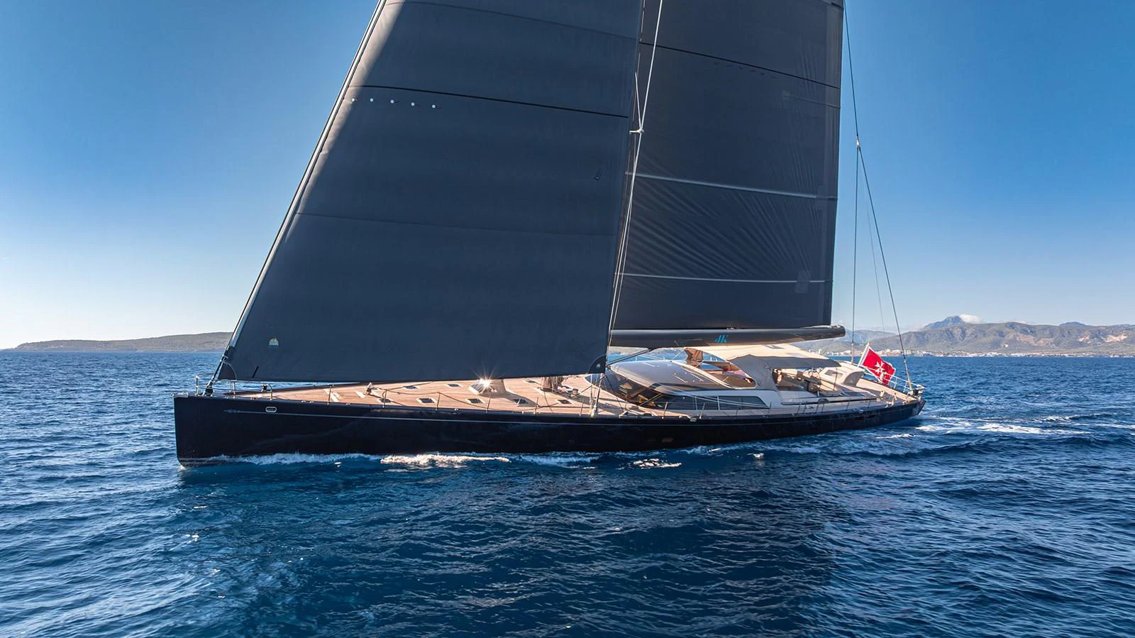 A sleek sailing yacht glides gracefully on the open sea under clear blue skies. aboard 4K Yacht for Sale