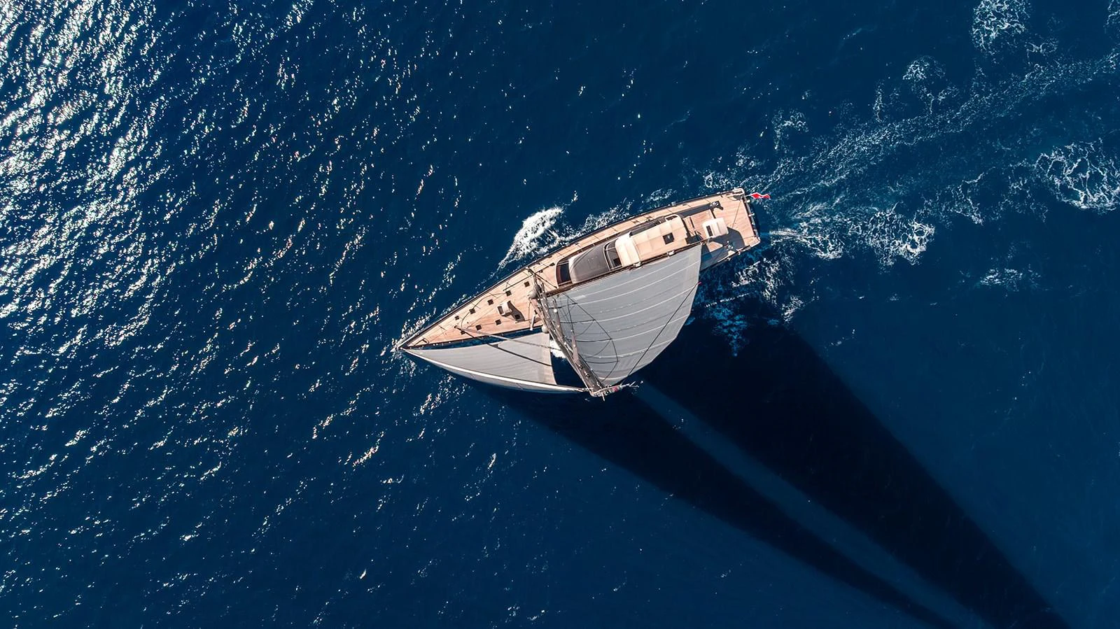 An elegant sailing yacht glides through the deep blue sea, captured from an aerial perspective. aboard 4K Yacht for Sale