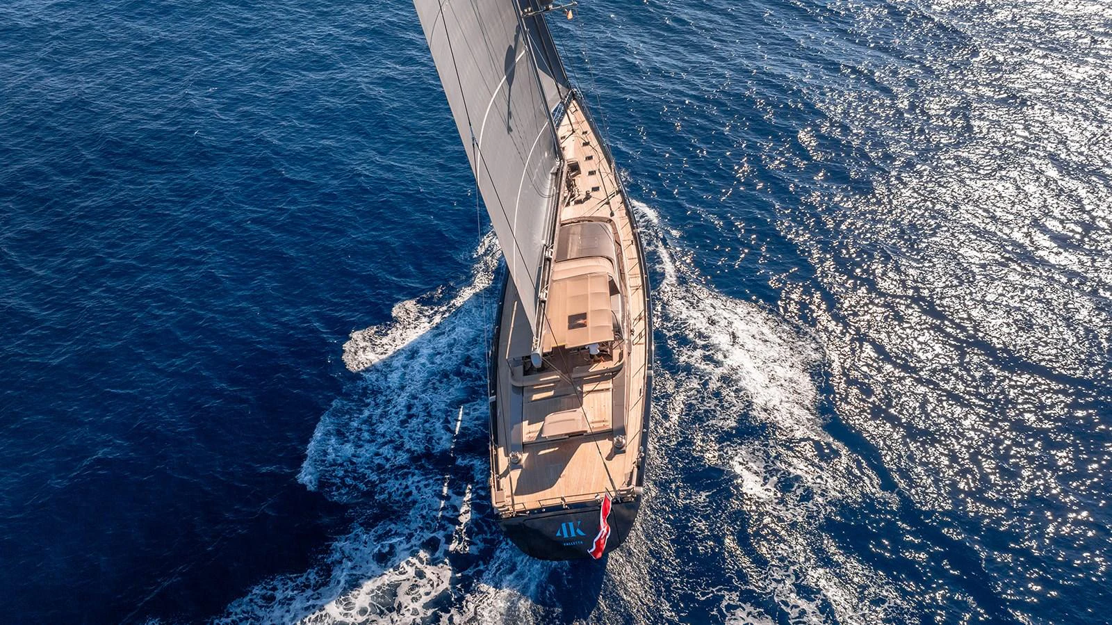 A stunning aerial view of a sailing yacht cutting through the deep blue sea. aboard 4K Yacht for Sale