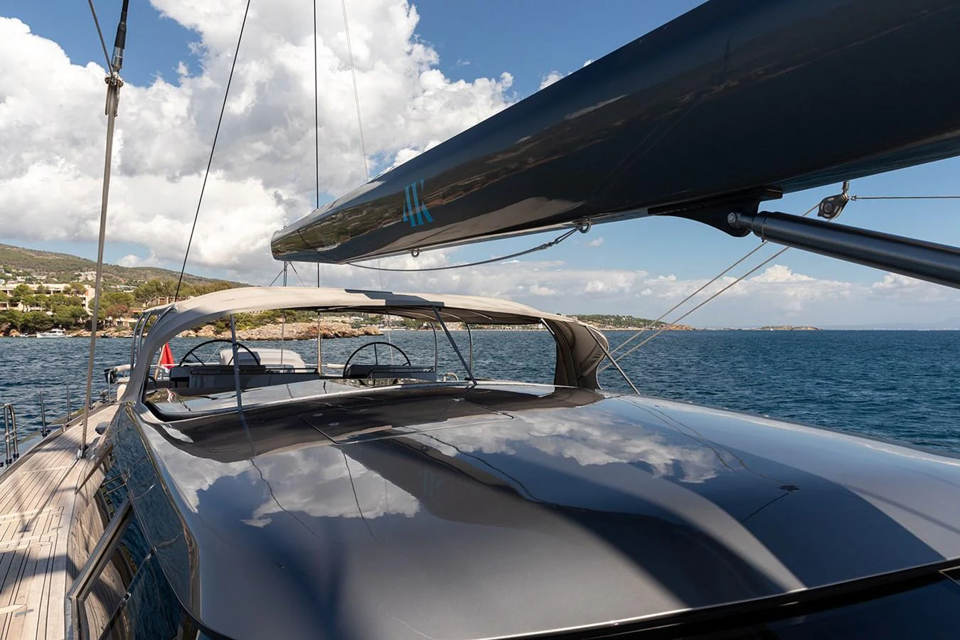 The sleek deck of a modern yacht is shown, with a clear view of the mast and boom under a bright sky. aboard 4K Yacht for Sale