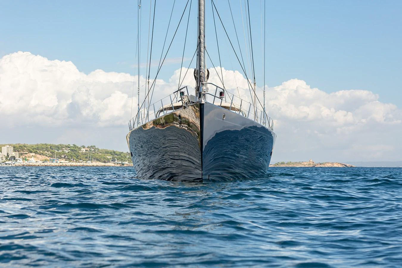 A sleek yacht is captured head-on, cutting through calm blue waters under a clear sky. aboard 4K Yacht for Sale