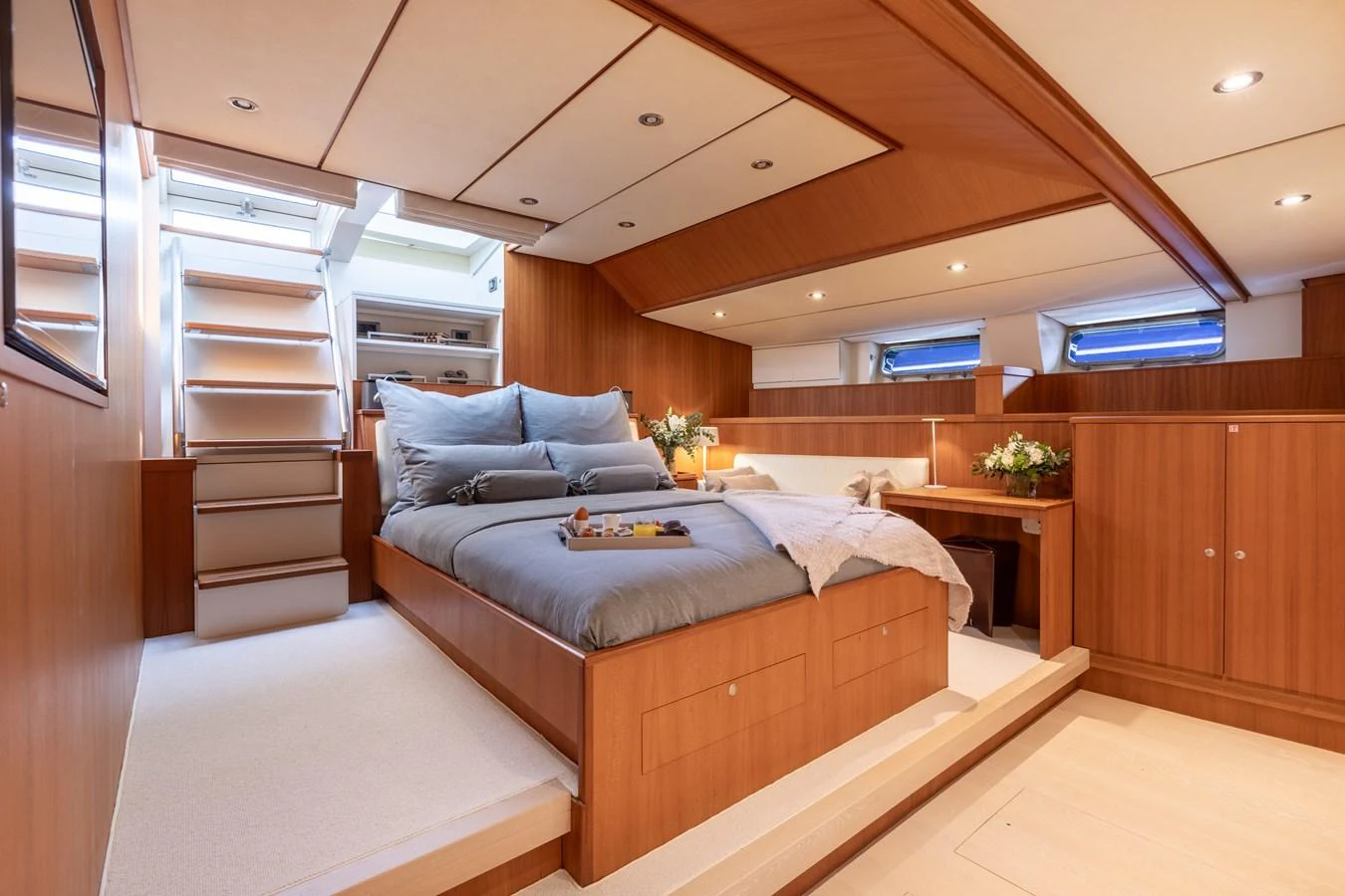 The master stateroom features a luxurious bed with elegant wood paneling and ample natural light. aboard 4K Yacht for Sale