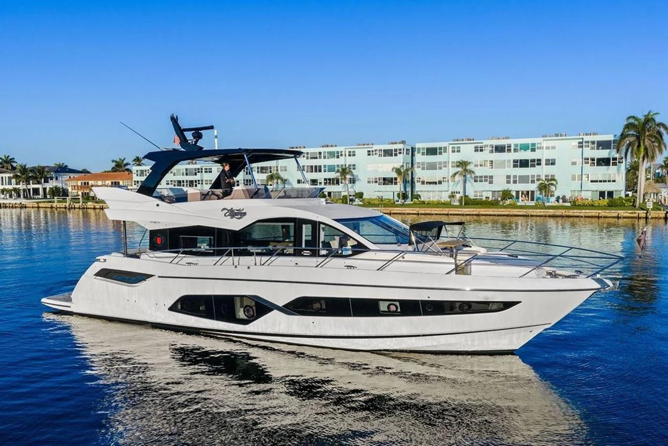 A sleek, modern yacht is docked in a serene waterfront setting with clear blue skies. aboard ELLIGANCE Yacht for Sale