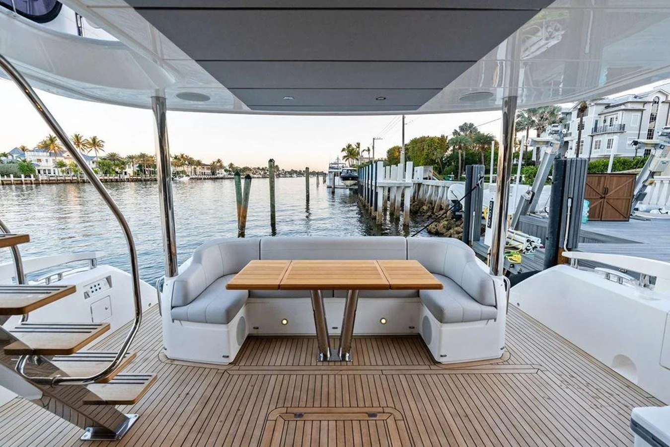 The aft deck features a comfortable seating area with a wooden table, perfect for enjoying waterfront views. aboard ELLIGANCE Yacht for Sale
