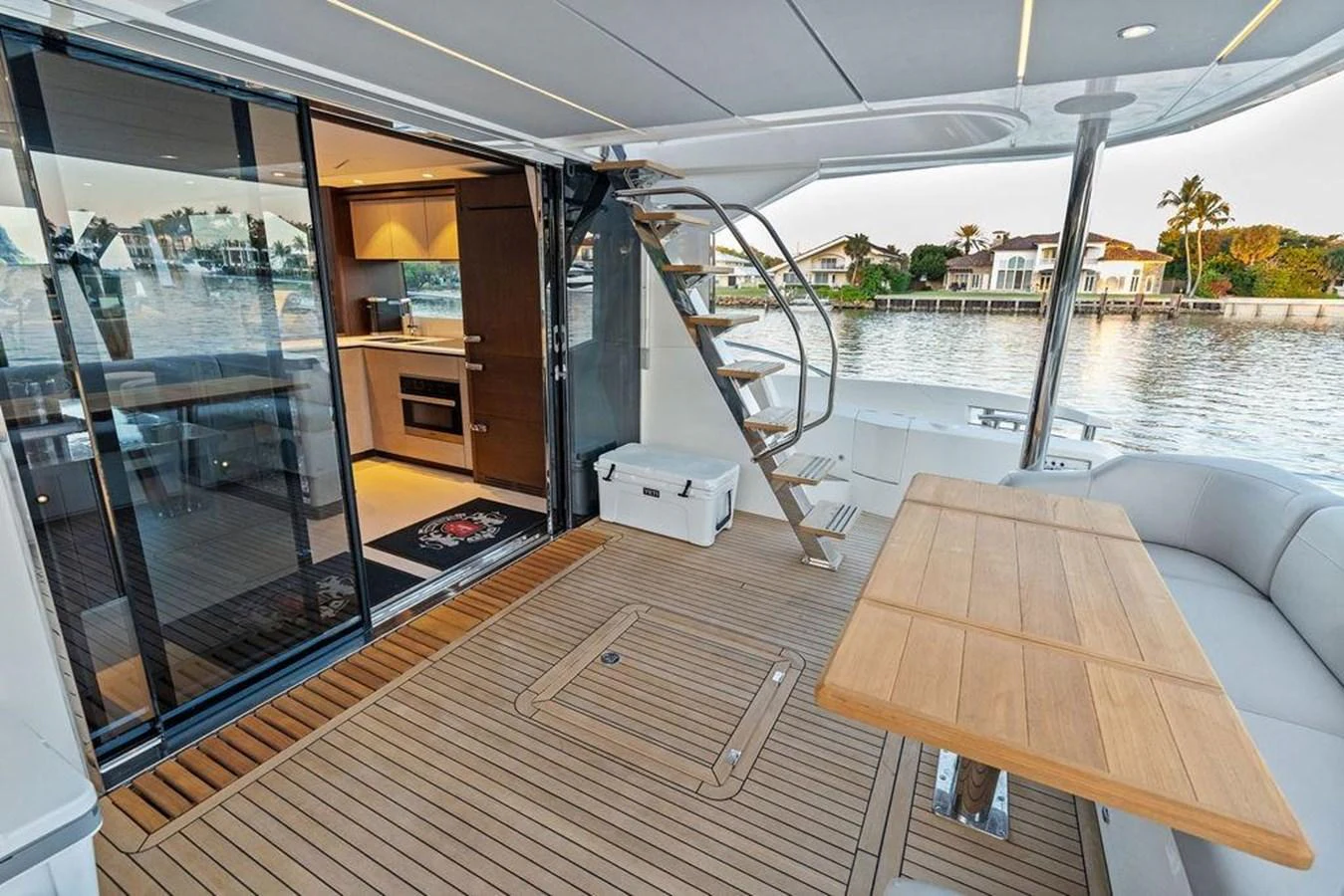 The aft deck features a stylish seating area with a wooden table and easy access to the interior through sliding glass doors. aboard ELLIGANCE Yacht for Sale