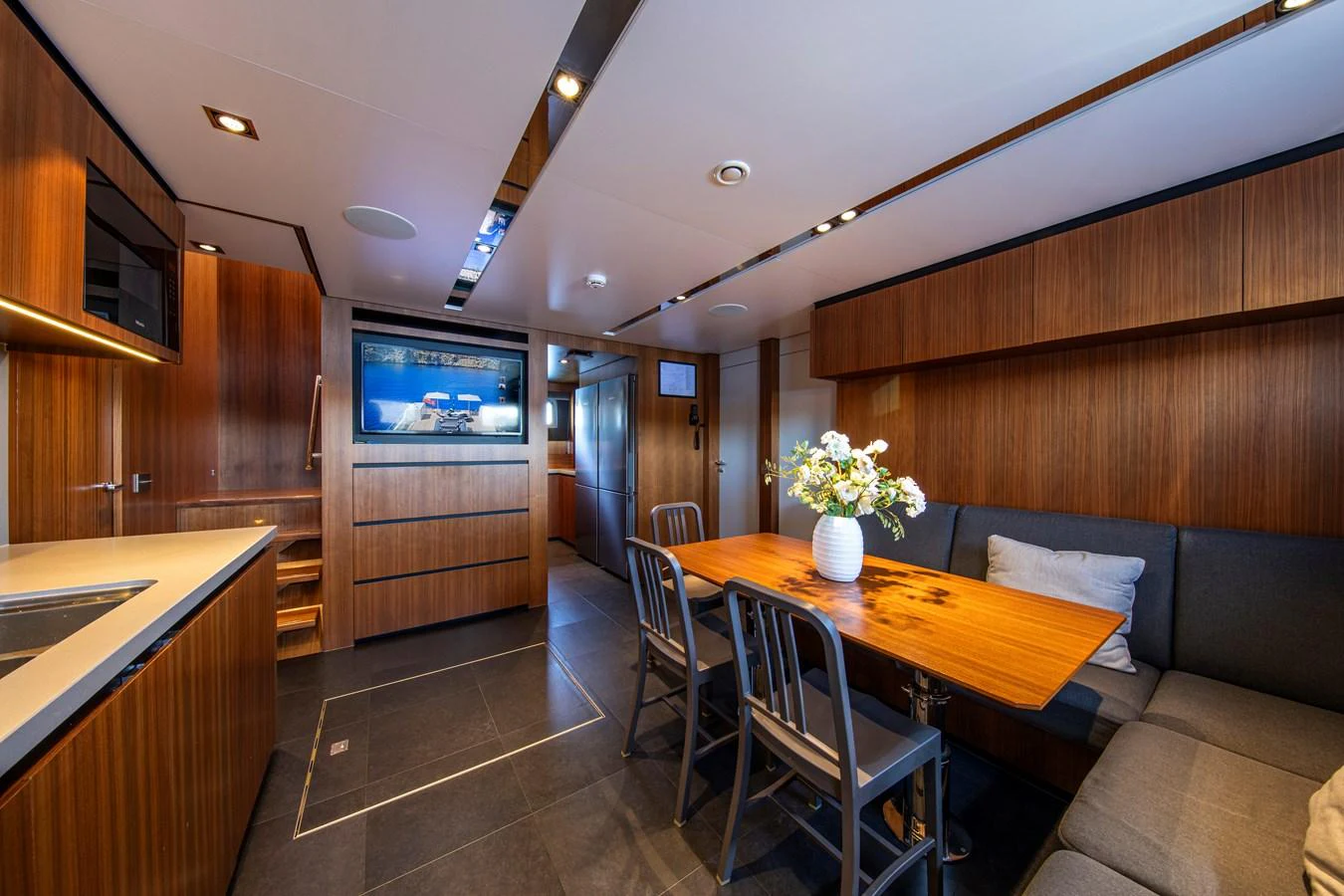 The yacht's dining area features a cozy seating arrangement with a wooden table and modern decor. aboard PLAYA Yacht for Sale
