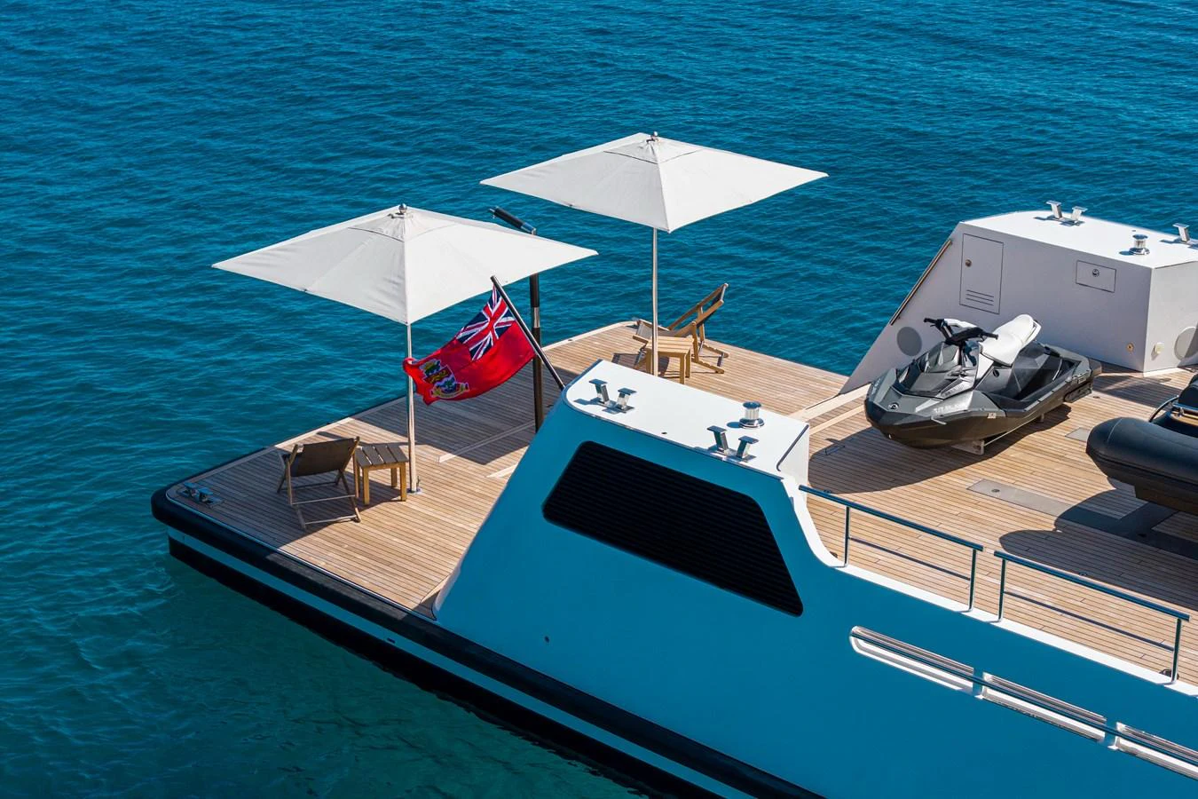 The aft deck features a spacious lounging area with sun umbrellas and a jet ski, perfect for relaxation and water activities. aboard PLAYA Yacht for Sale