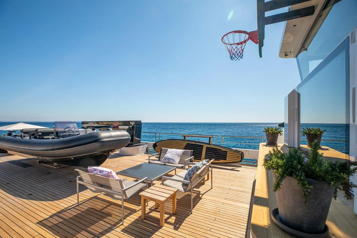 The aft deck features a relaxing lounge area with a basketball hoop and stunning ocean views. aboard PLAYA Yacht for Sale
