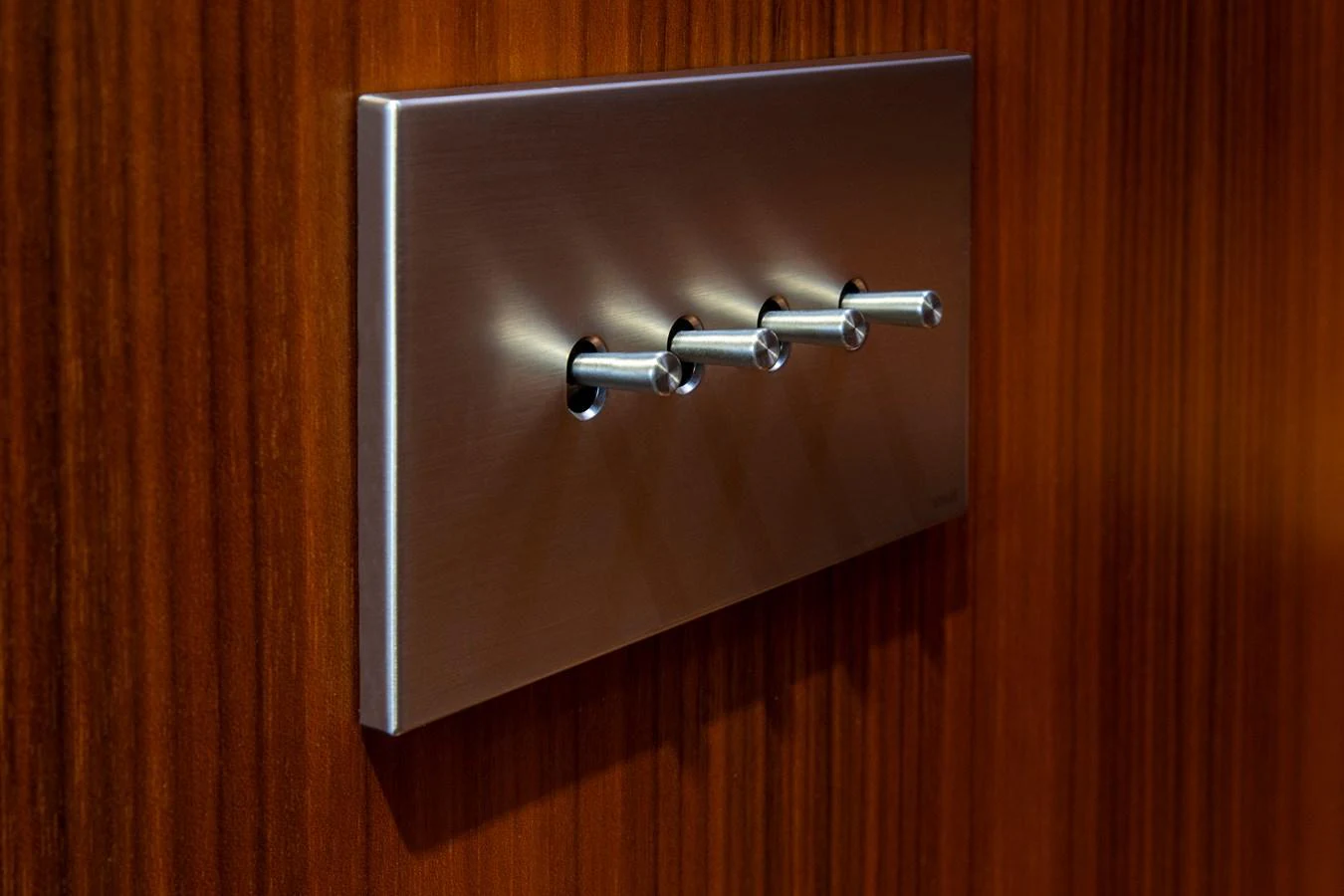 A sleek, modern light switch panel is mounted on a polished wooden surface. aboard PLAYA Yacht for Sale