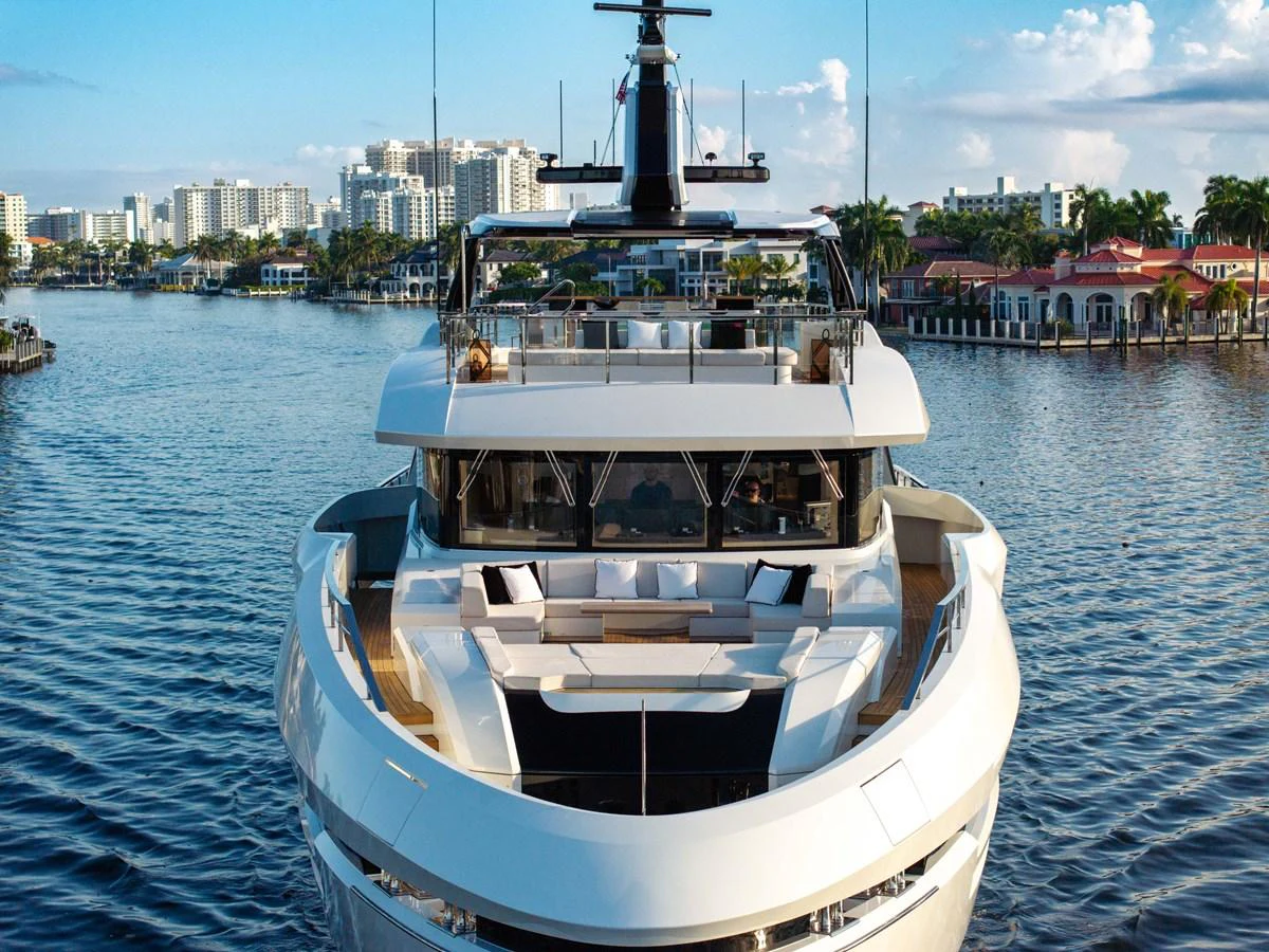 A luxurious yacht is docked in a serene marina with a cityscape in the background. aboard BAGLIETTO DOM 133 #5 Yacht for Sale