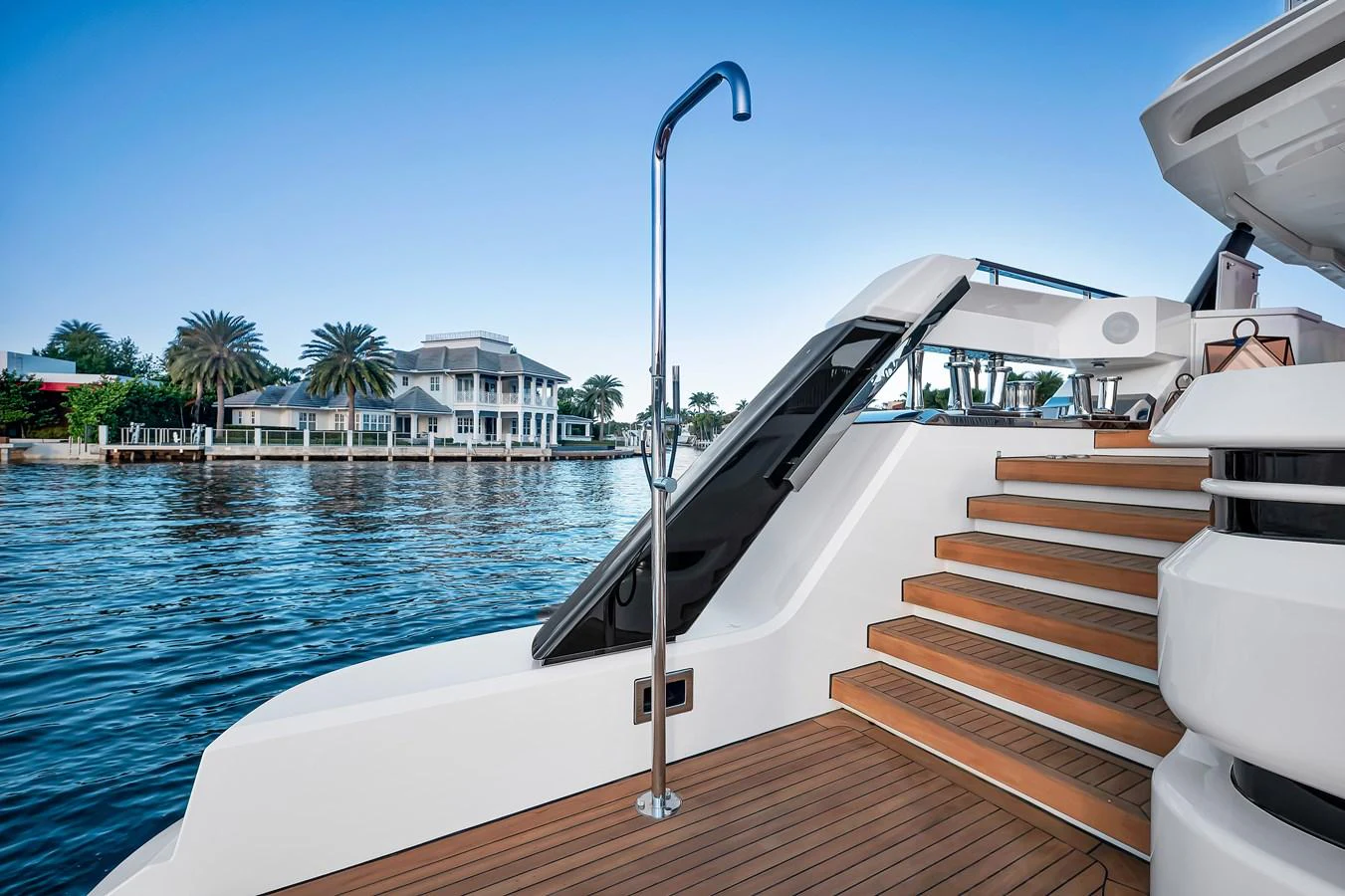 The aft deck features elegant wooden steps leading up to the main deck, with a view of the serene waterfront. aboard BAGLIETTO DOM 133 #5 Yacht for Sale