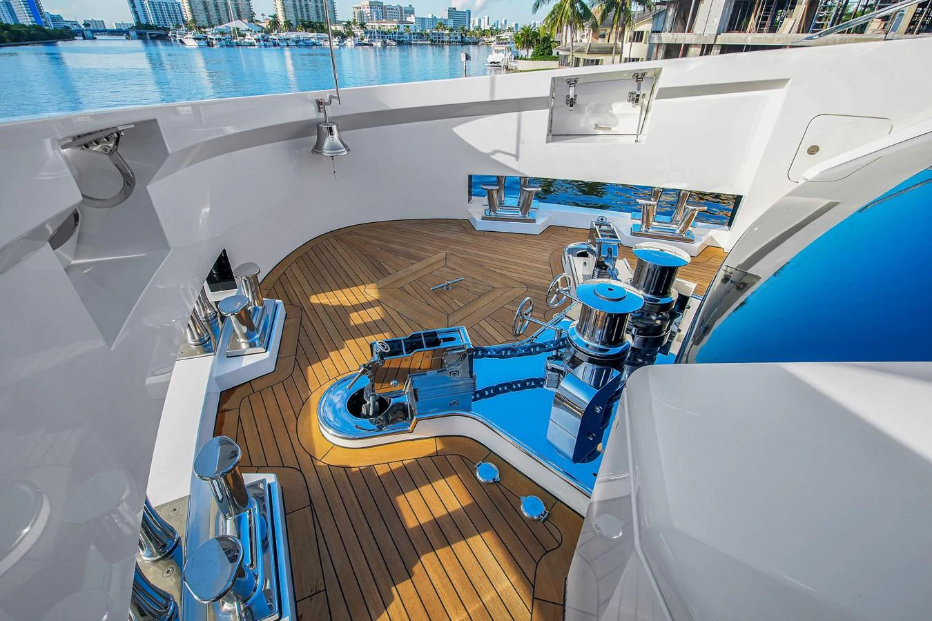 The foredeck showcases polished stainless steel fittings and a pristine teak deck, with a backdrop of a serene marina. aboard BAGLIETTO DOM 133 #5 Yacht for Sale