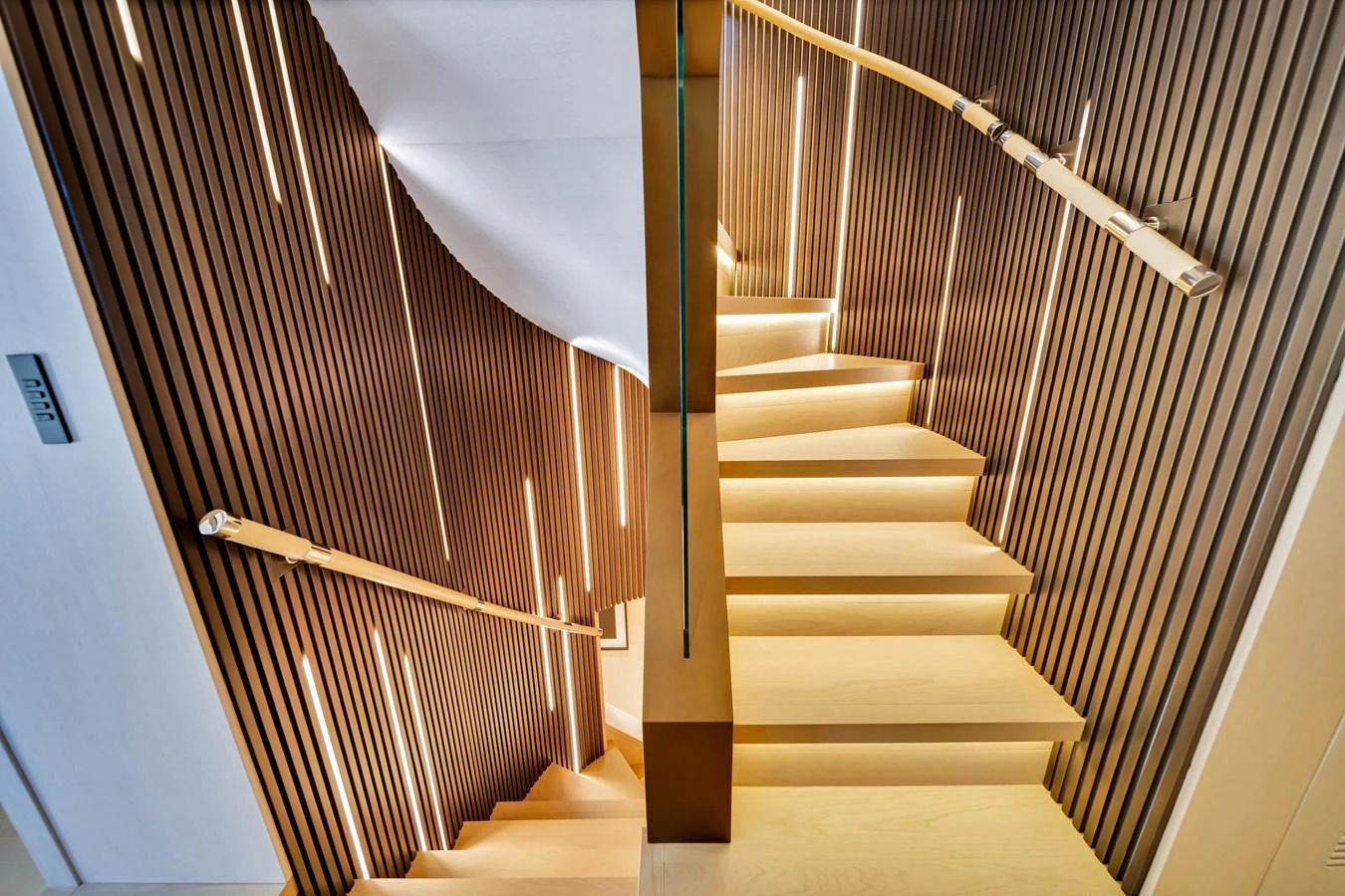 A modern and elegant staircase with wooden steps and sleek handrails, illuminated by stylish lighting. aboard BAGLIETTO DOM 133 #5 Yacht for Sale