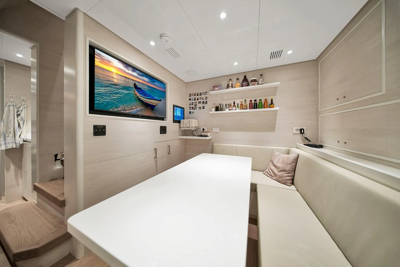 A cozy interior dining area with a modern design and a large screen displaying a serene beach scene. aboard BAGLIETTO DOM 133 #5 Yacht for Sale