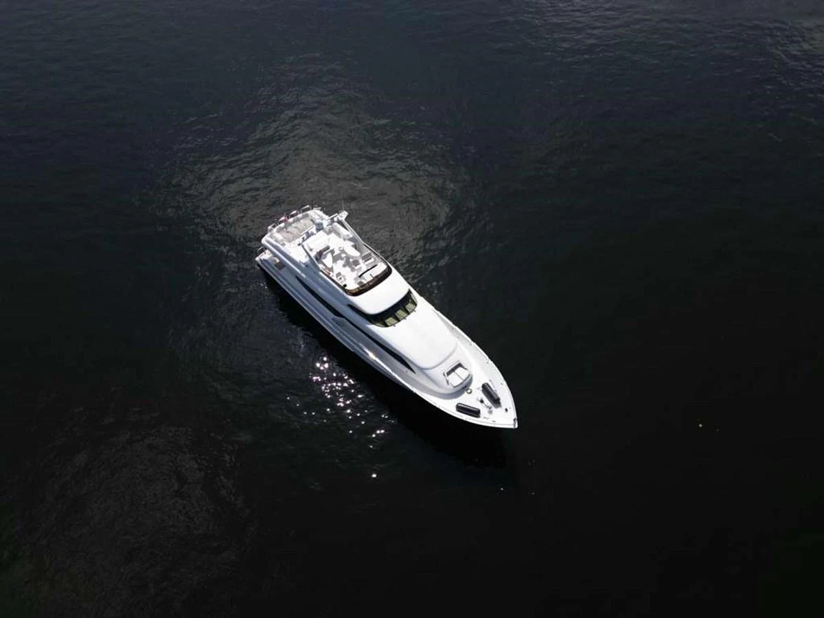 A sleek white yacht glides gracefully on calm, dark waters. aboard TRANQUILITY IV - 94 FT LAZZARA MOTORYACHT 2001 Yacht for Sale