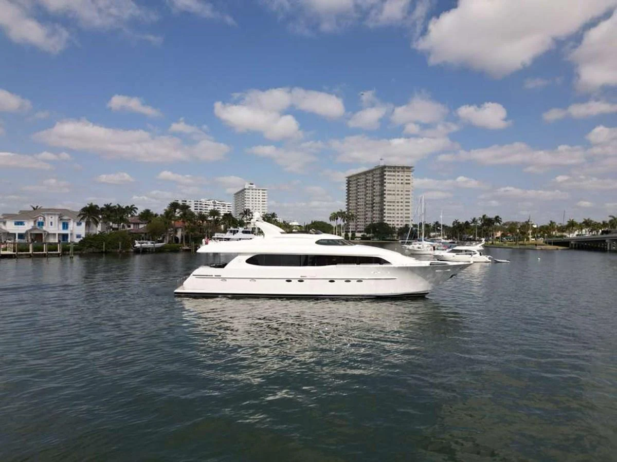 A sleek white yacht cruises through a calm marina under a partly cloudy sky. aboard TRANQUILITY IV - 94 FT LAZZARA MOTORYACHT 2001 Yacht for Sale