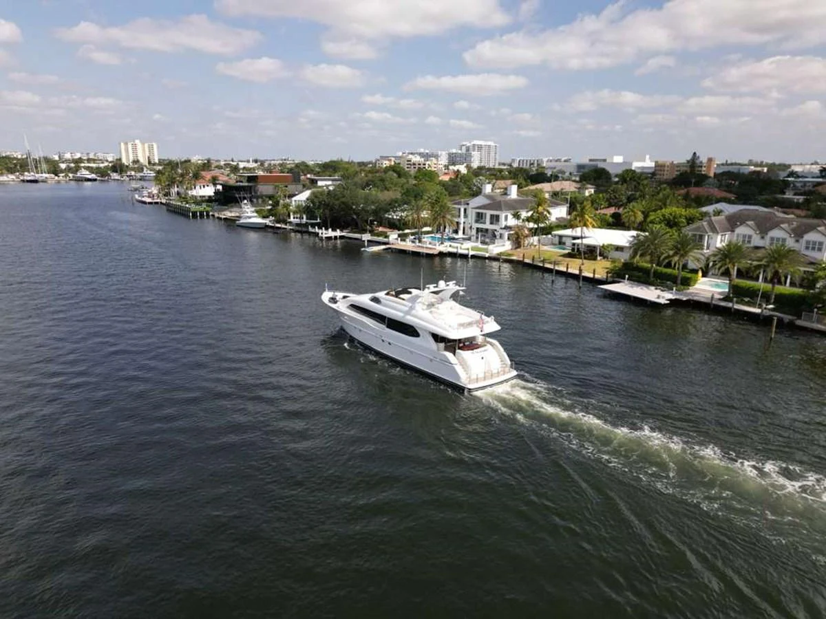 A sleek yacht cruises through a serene waterway, showcasing its elegant design against a backdrop of waterfront homes. aboard TRANQUILITY IV - 94 FT LAZZARA MOTORYACHT 2001 Yacht for Sale