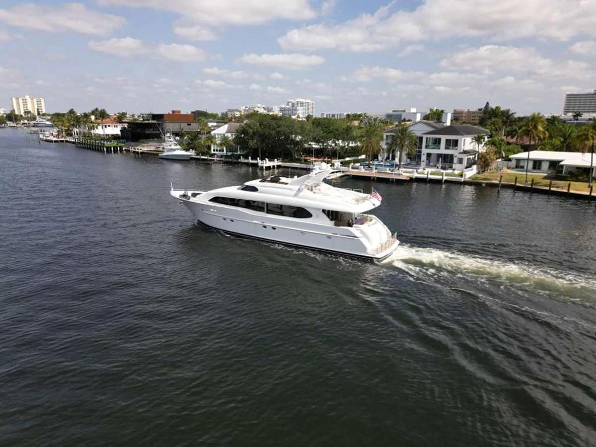 A sleek white yacht cruises along a scenic waterfront with modern homes in the background. aboard TRANQUILITY IV - 94 FT LAZZARA MOTORYACHT 2001 Yacht for Sale