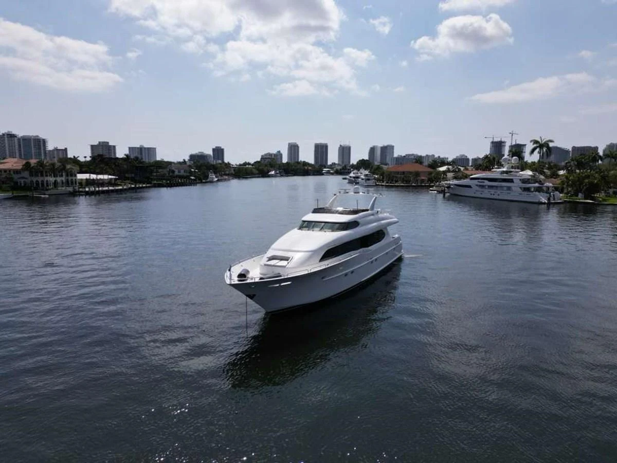 A sleek yacht cruises gracefully through a serene waterway with a cityscape in the background. aboard TRANQUILITY IV - 94 FT LAZZARA MOTORYACHT 2001 Yacht for Sale
