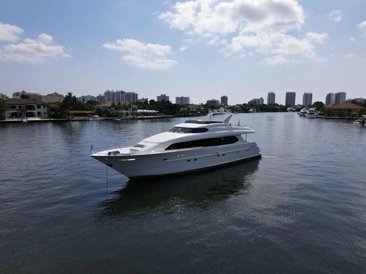 A sleek white yacht glides gracefully on calm waters with a cityscape in the background. aboard TRANQUILITY IV - 94 FT LAZZARA MOTORYACHT 2001 Yacht for Sale