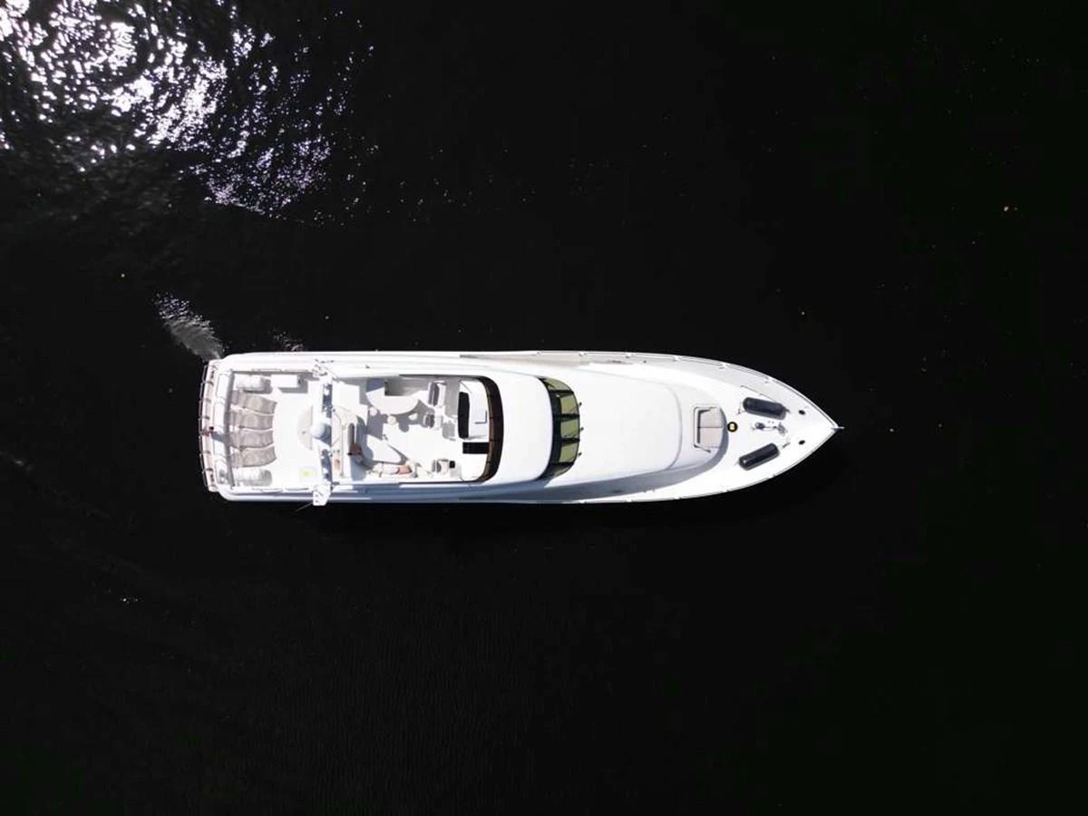 An aerial view of a sleek yacht cruising through dark waters, showcasing its elegant design and spacious deck layout. aboard TRANQUILITY IV - 94 FT LAZZARA MOTORYACHT 2001 Yacht for Sale