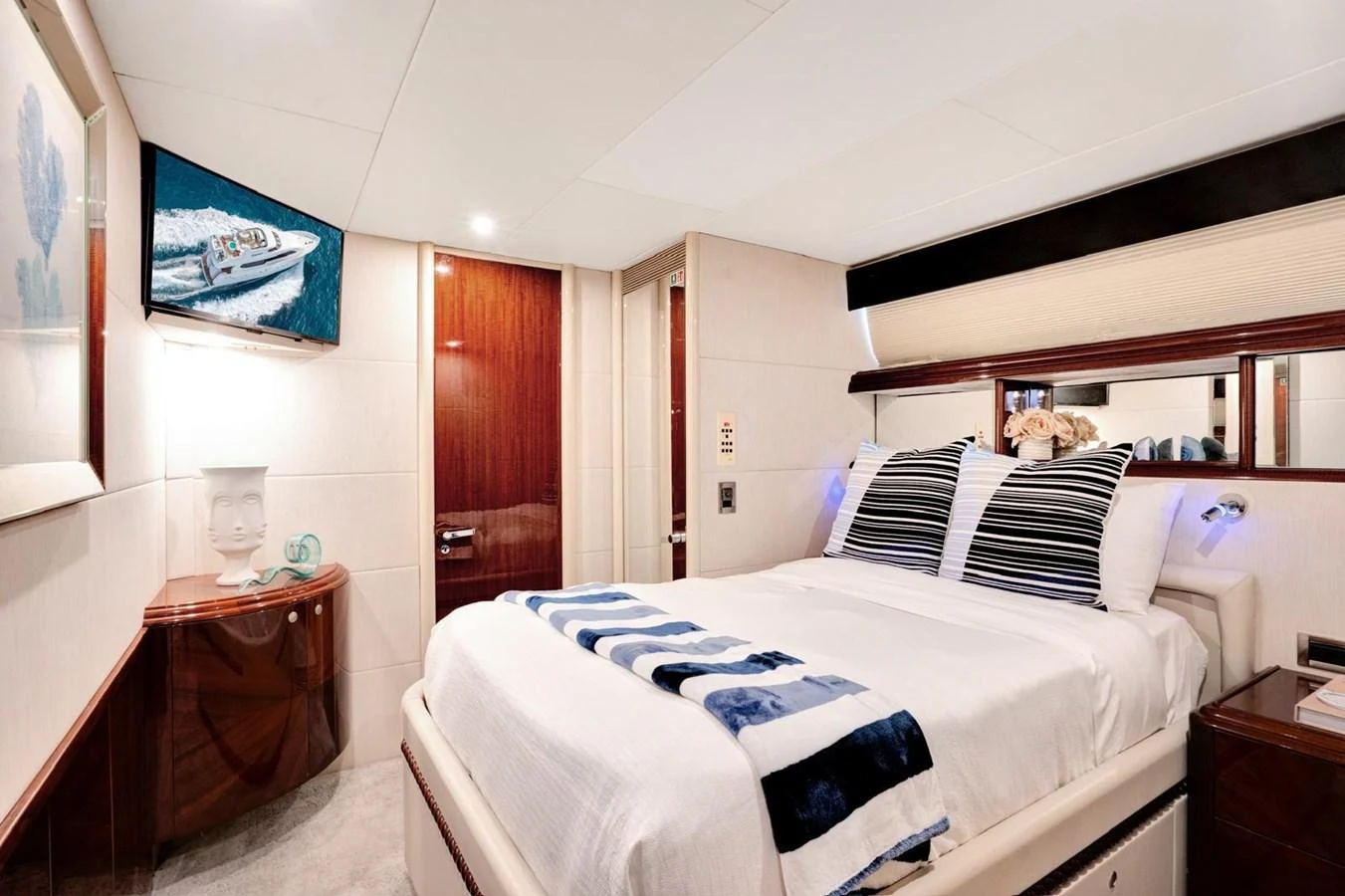 A luxurious stateroom featuring a comfortable bed, elegant decor, and a mounted TV. aboard TRANQUILITY IV - 94 FT LAZZARA MOTORYACHT 2001 Yacht for Sale