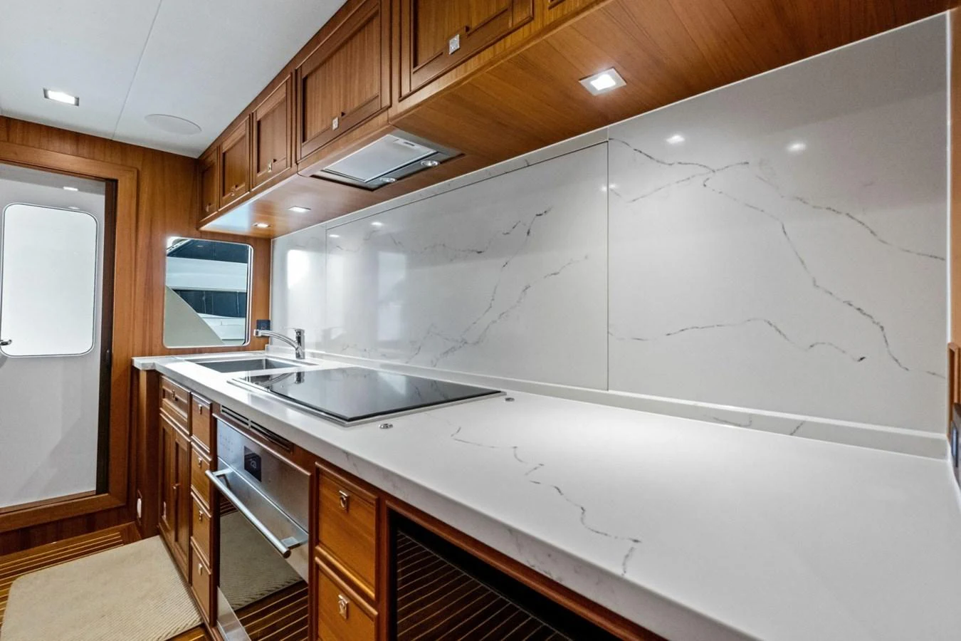 The yacht's galley features sleek wooden cabinetry and a pristine marble countertop, creating a modern and functional cooking space. aboard ARTEMIS II Yacht for Sale