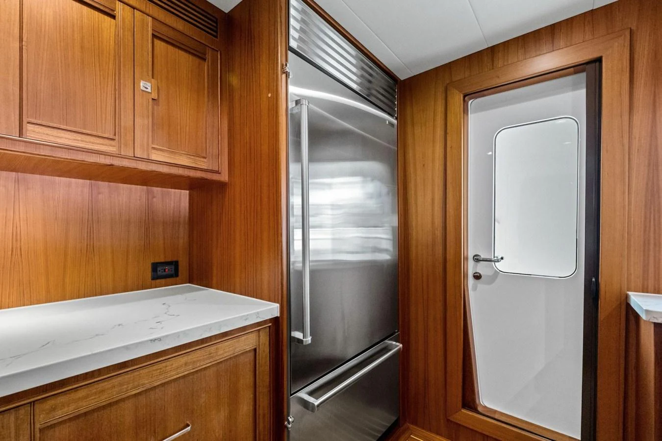 The galley features sleek wooden cabinetry and a modern stainless steel refrigerator. aboard ARTEMIS II Yacht for Sale