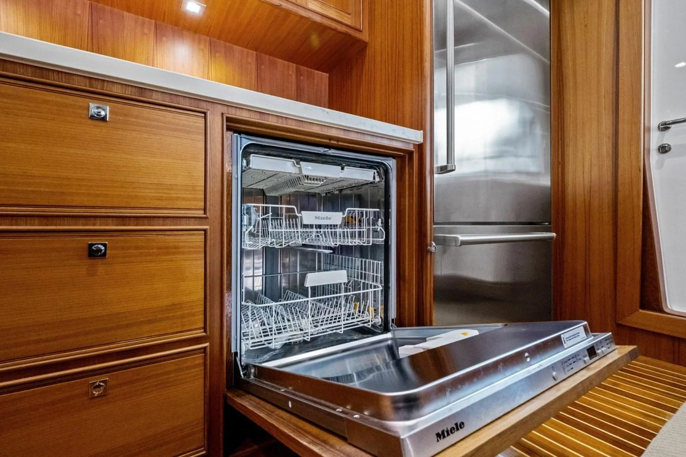 The galley features a built-in dishwasher and stainless steel refrigerator, surrounded by rich wooden cabinetry. aboard ARTEMIS II Yacht for Sale