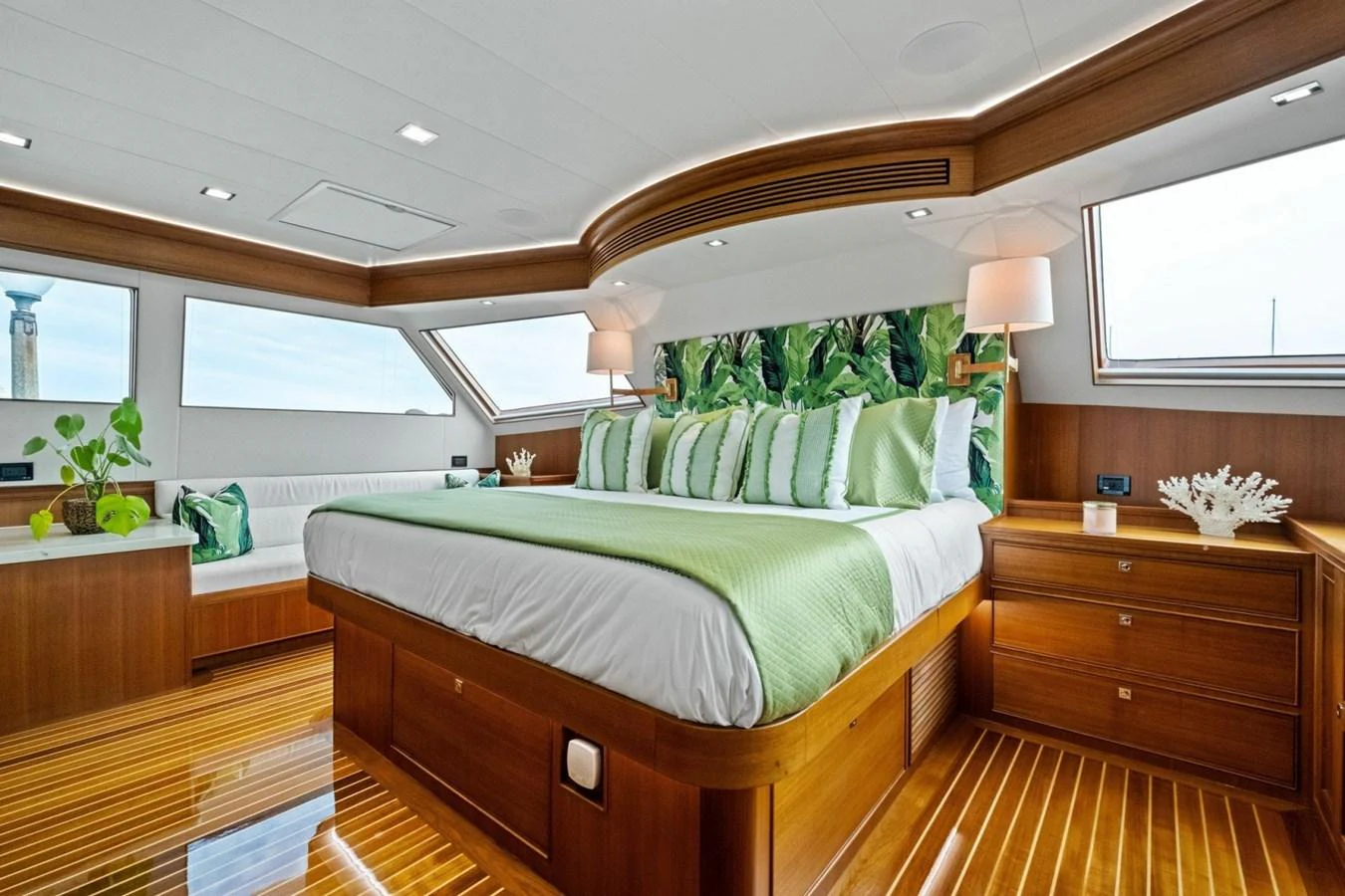 The master stateroom features a luxurious bed with green accents and ample natural light from large windows. aboard ARTEMIS II Yacht for Sale