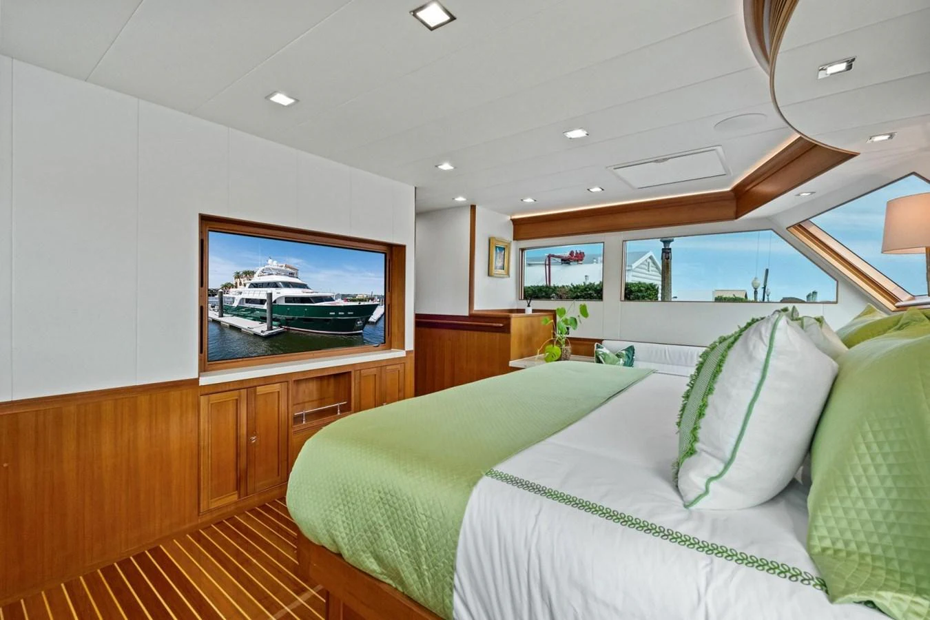 A luxurious stateroom featuring a large bed with green accents and a view of the outside through a window. aboard ARTEMIS II Yacht for Sale