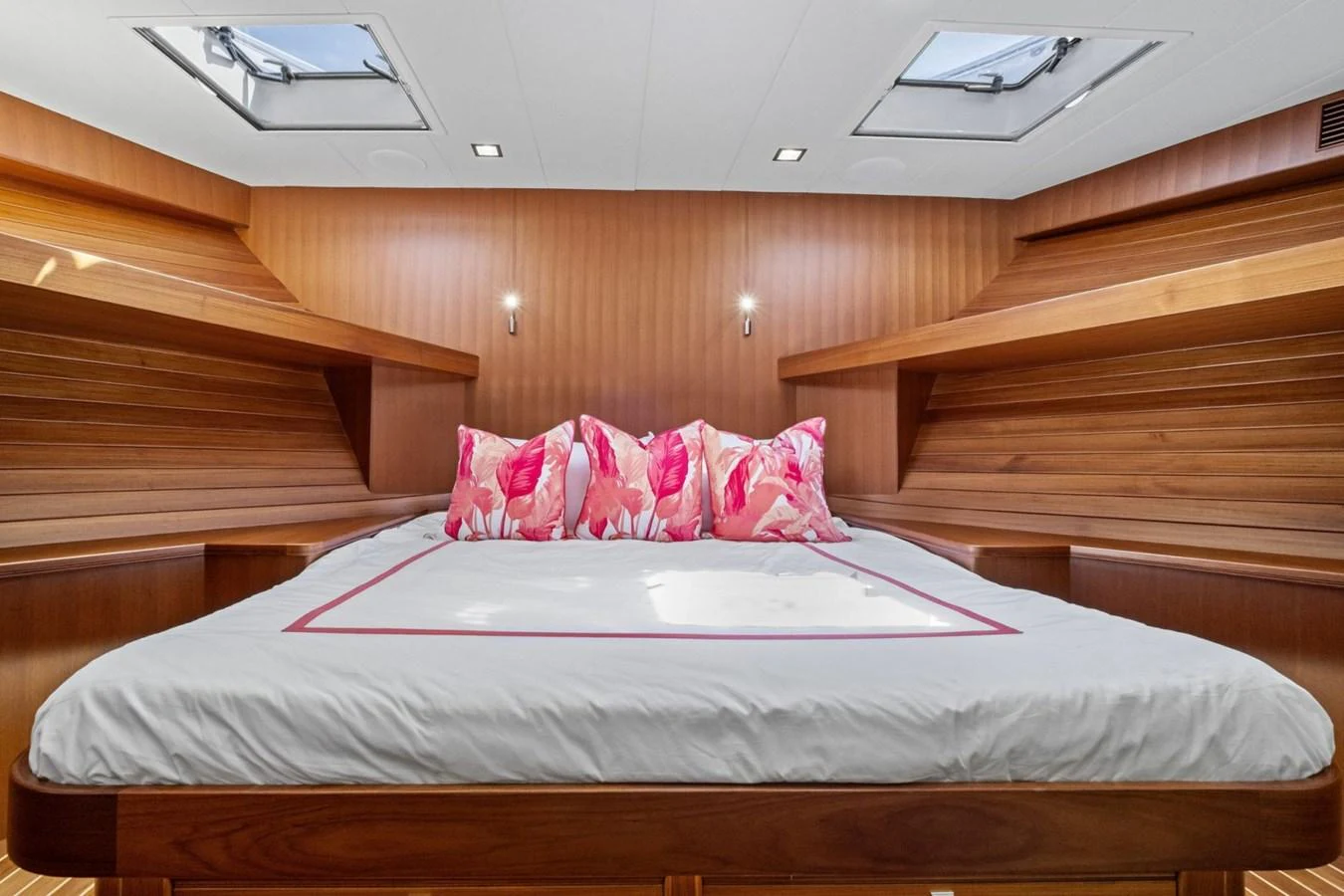 The stateroom features a cozy bed with vibrant pillows and ample natural light from overhead skylights. aboard ARTEMIS II Yacht for Sale