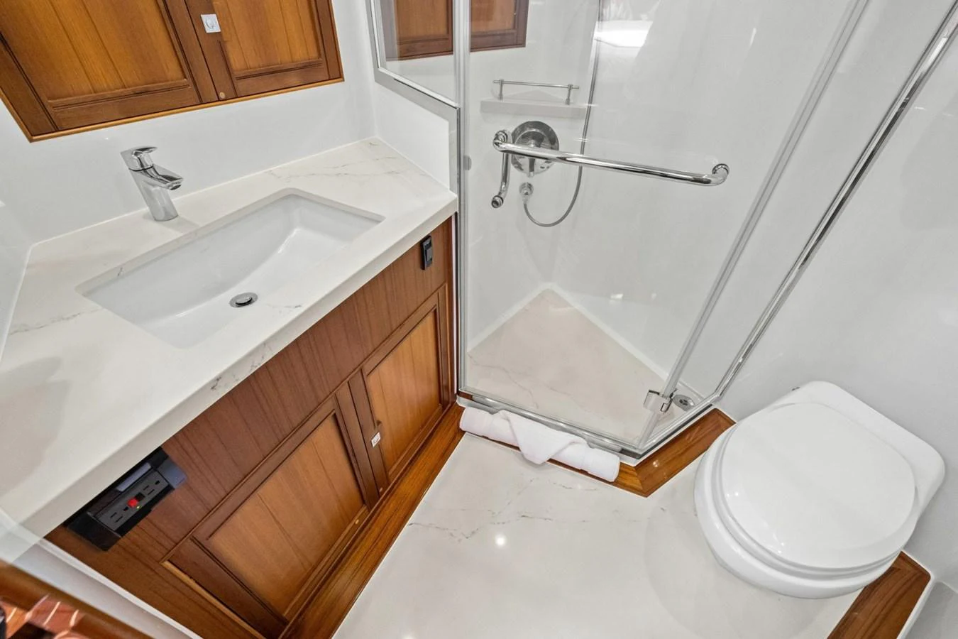 A well-appointed yacht bathroom featuring a sleek sink, wooden cabinetry, and a glass-enclosed shower. aboard ARTEMIS II Yacht for Sale