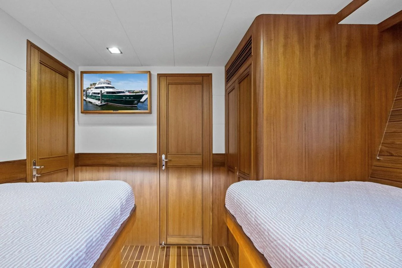 The guest cabin features twin beds with a warm wooden finish and a yacht-themed artwork on the wall. aboard ARTEMIS II Yacht for Sale